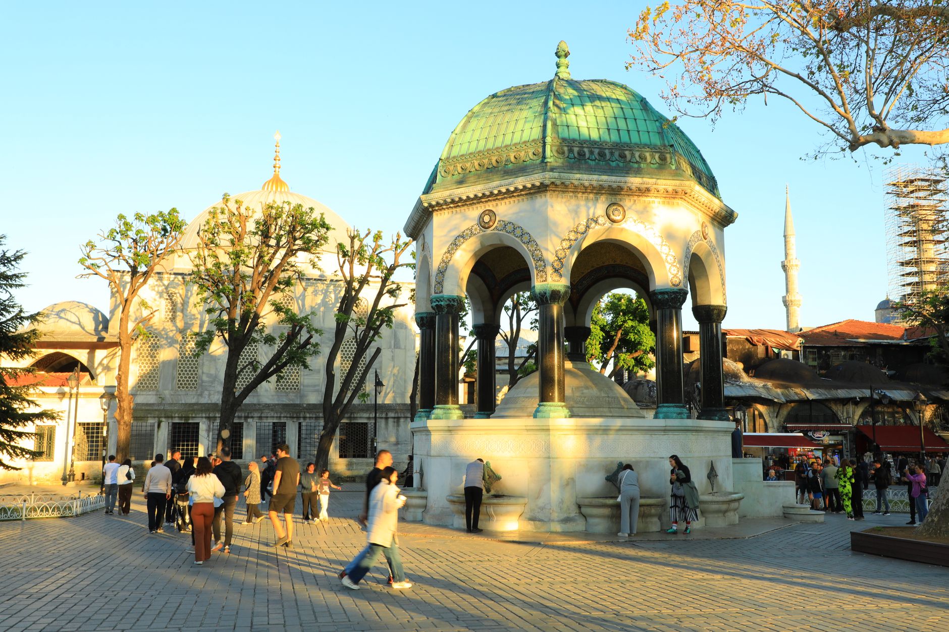 People enjoying a sunny day at the historic German Fountain, Istanbul, Türkiye.