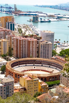 A stunning aerial view of Málaga, featuring the iconic bullring and bustling port area in Andalusia, Spain.