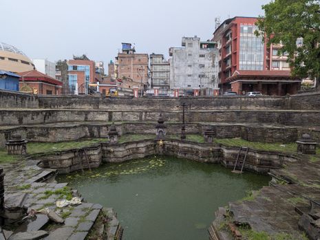 Ancient stone pond surrounded by historic architecture in Kathmandu, Nepal.