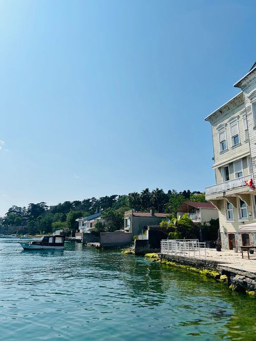Free Charming waterfront view with boat and houses under clear blue sky. Stock Photo
