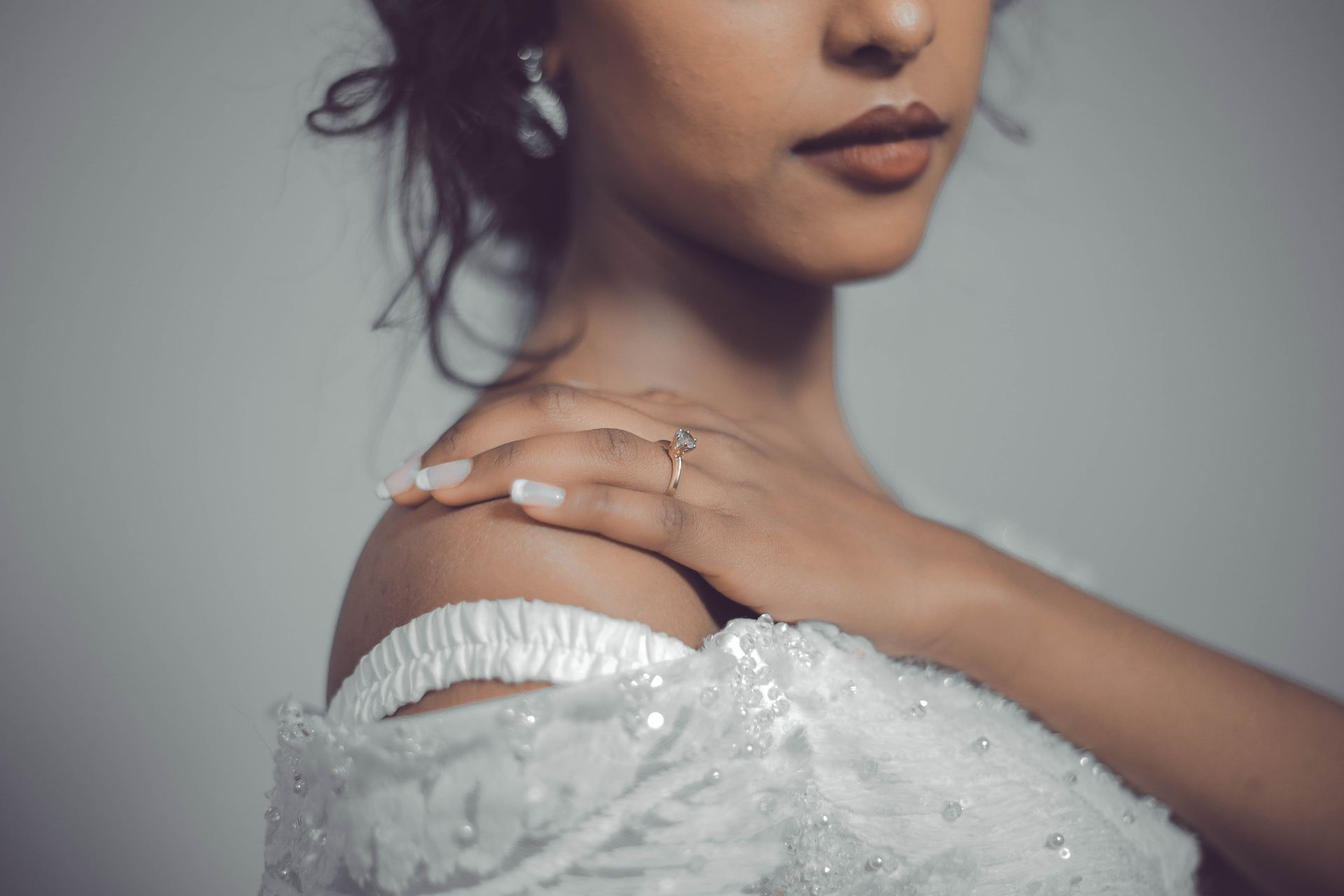 A close-up of a bride showcasing elegant jewelry and a wedding dress.
