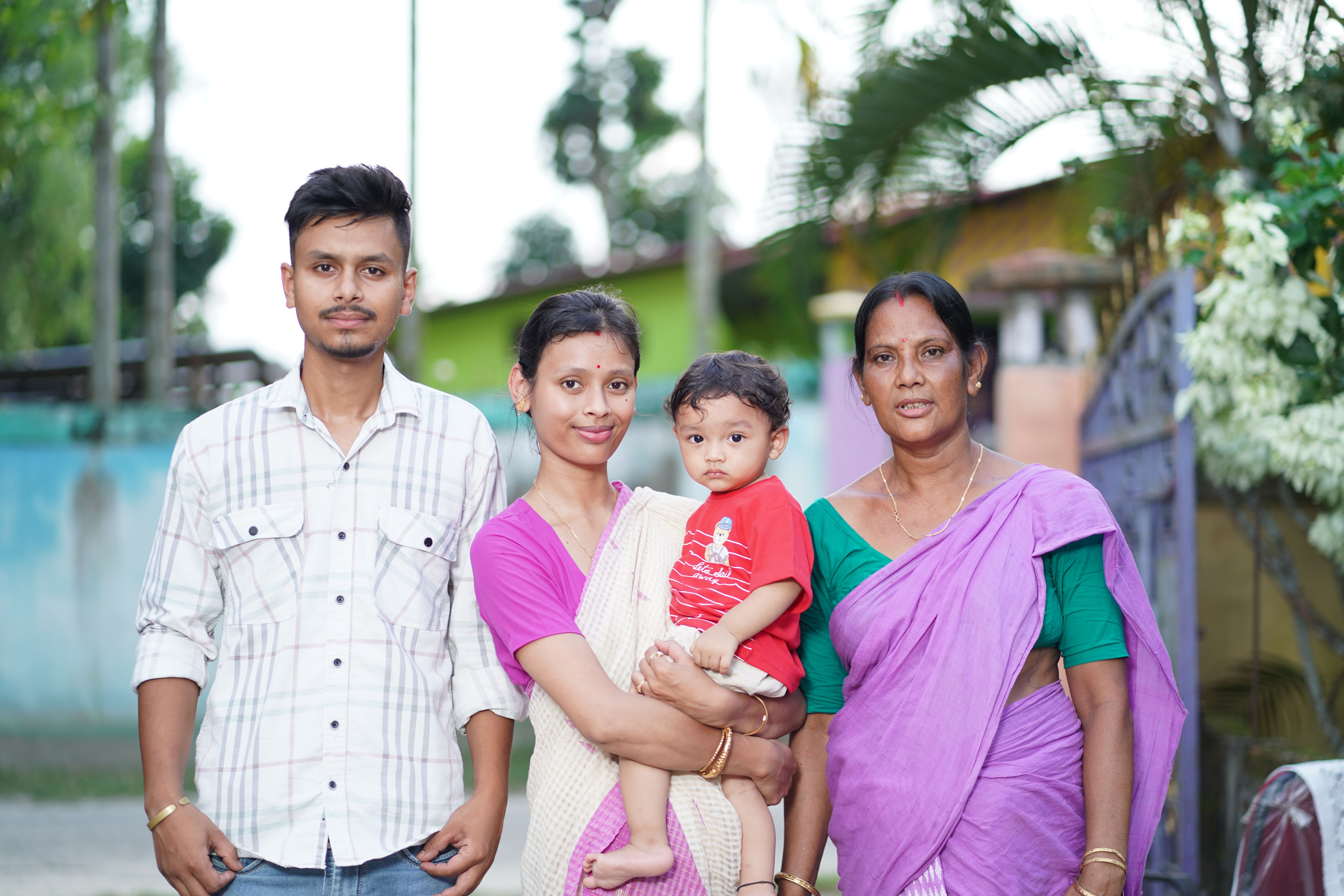 A happy family posing outdoors, showcasing generational bonding and traditional attire.