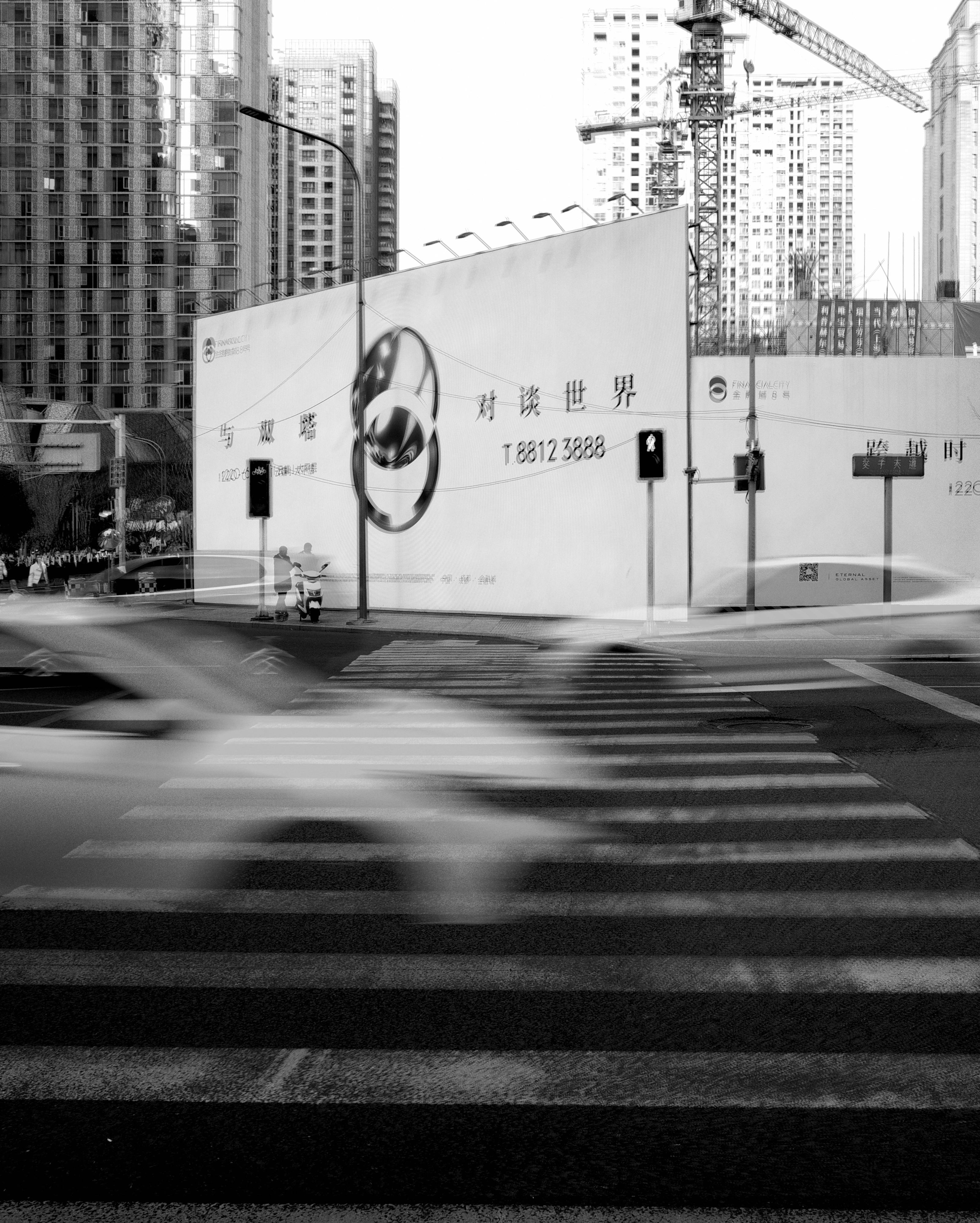 A bustling city intersection in motion with blurred vehicles and towering skyscrapers.