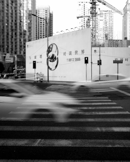 A bustling city intersection in motion with blurred vehicles and towering skyscrapers.
