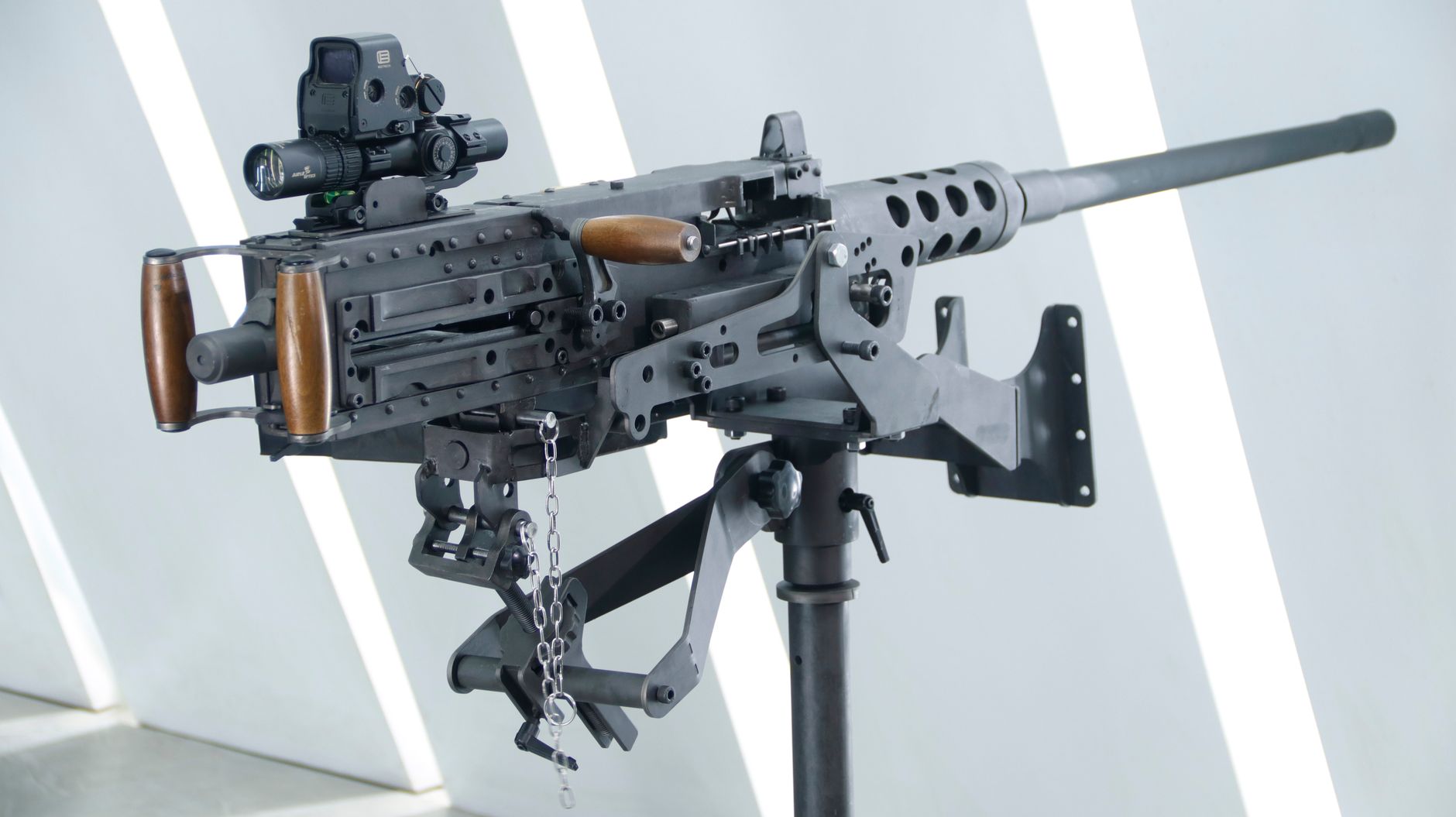 Detailed view of a heavy machine gun mounted on a stand with a modern background.