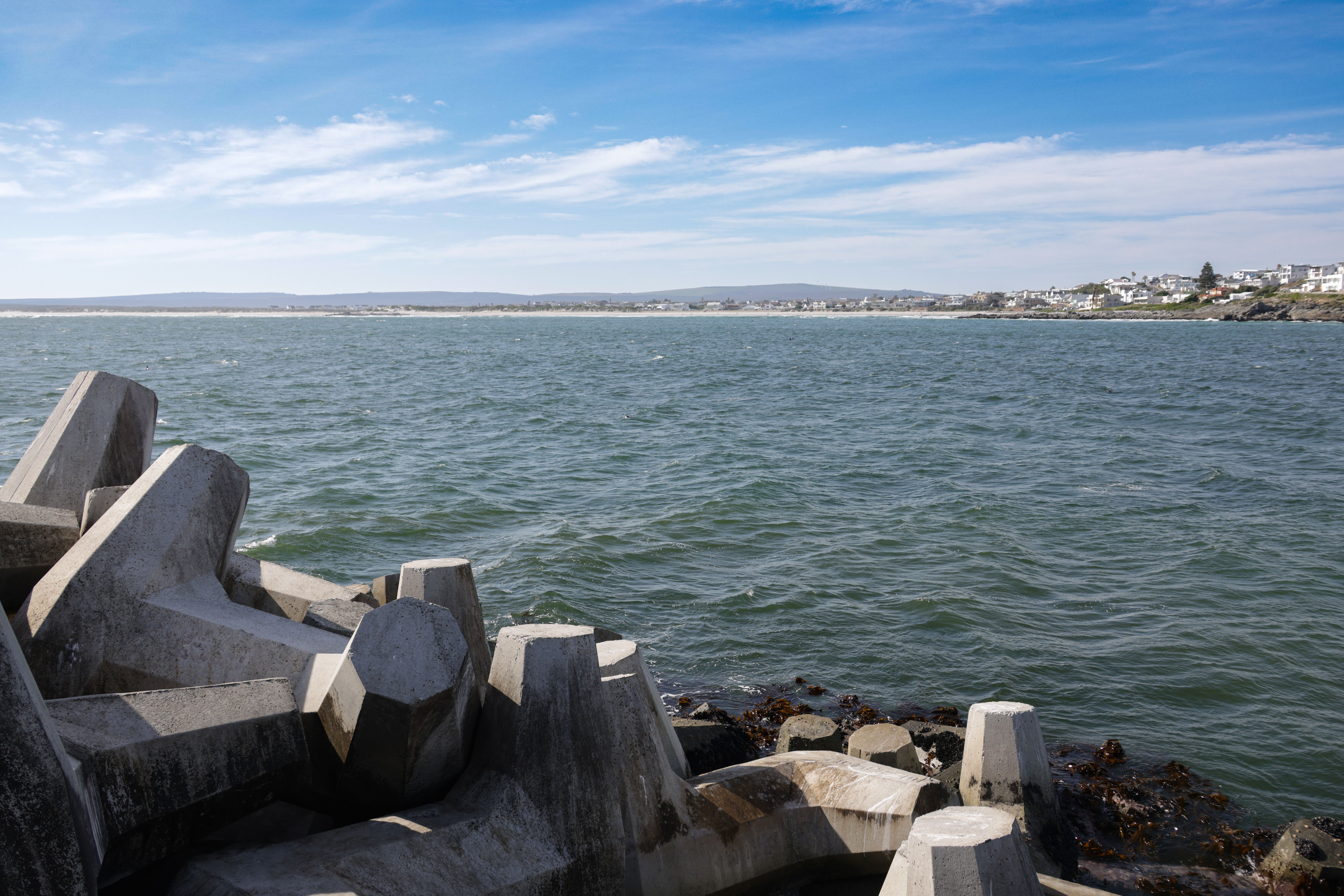 Concrete tetrapods along a coastal shoreline under a bright blue sky.