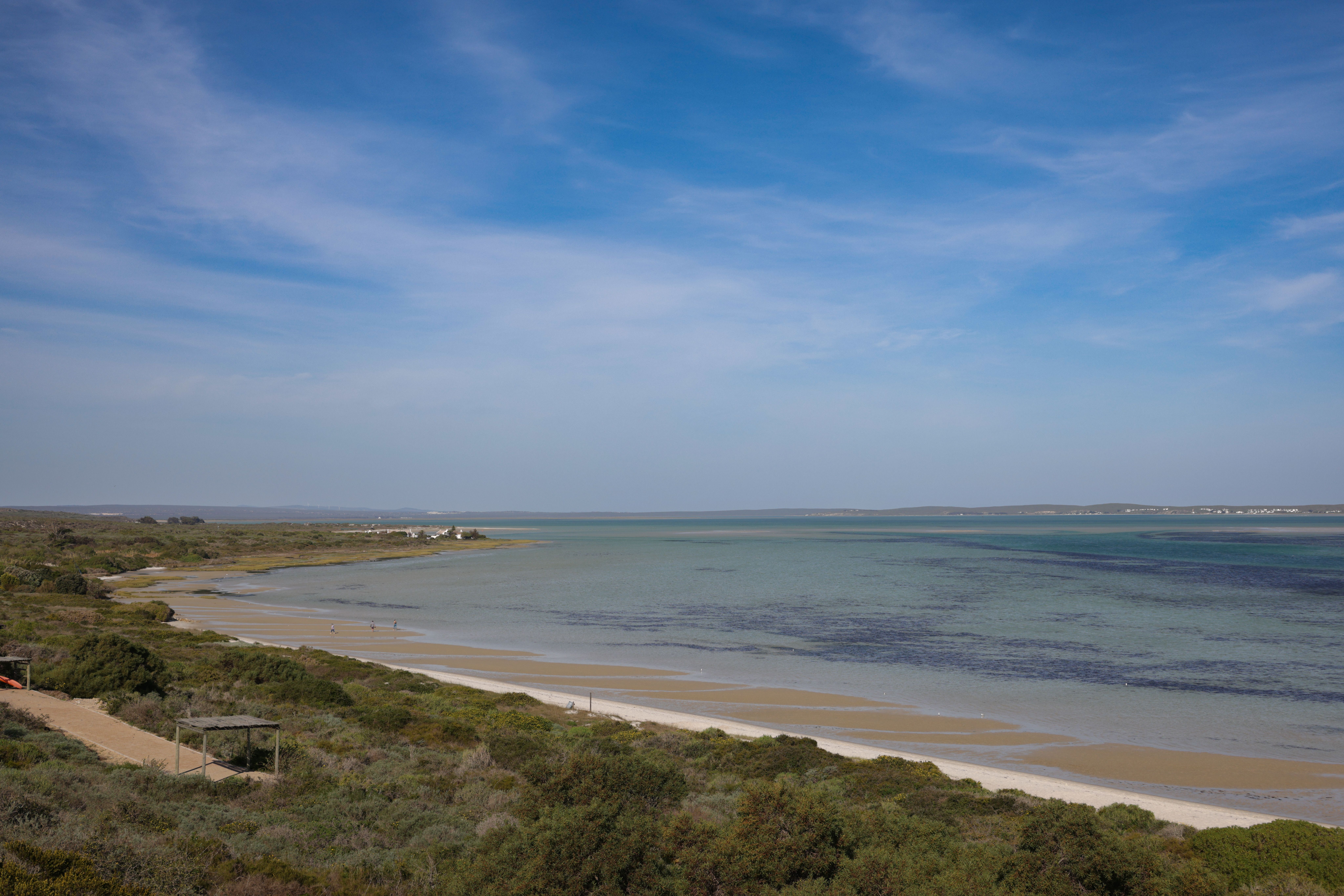 A serene coastal landscape with calm ocean waves and blue sky in South Africa.