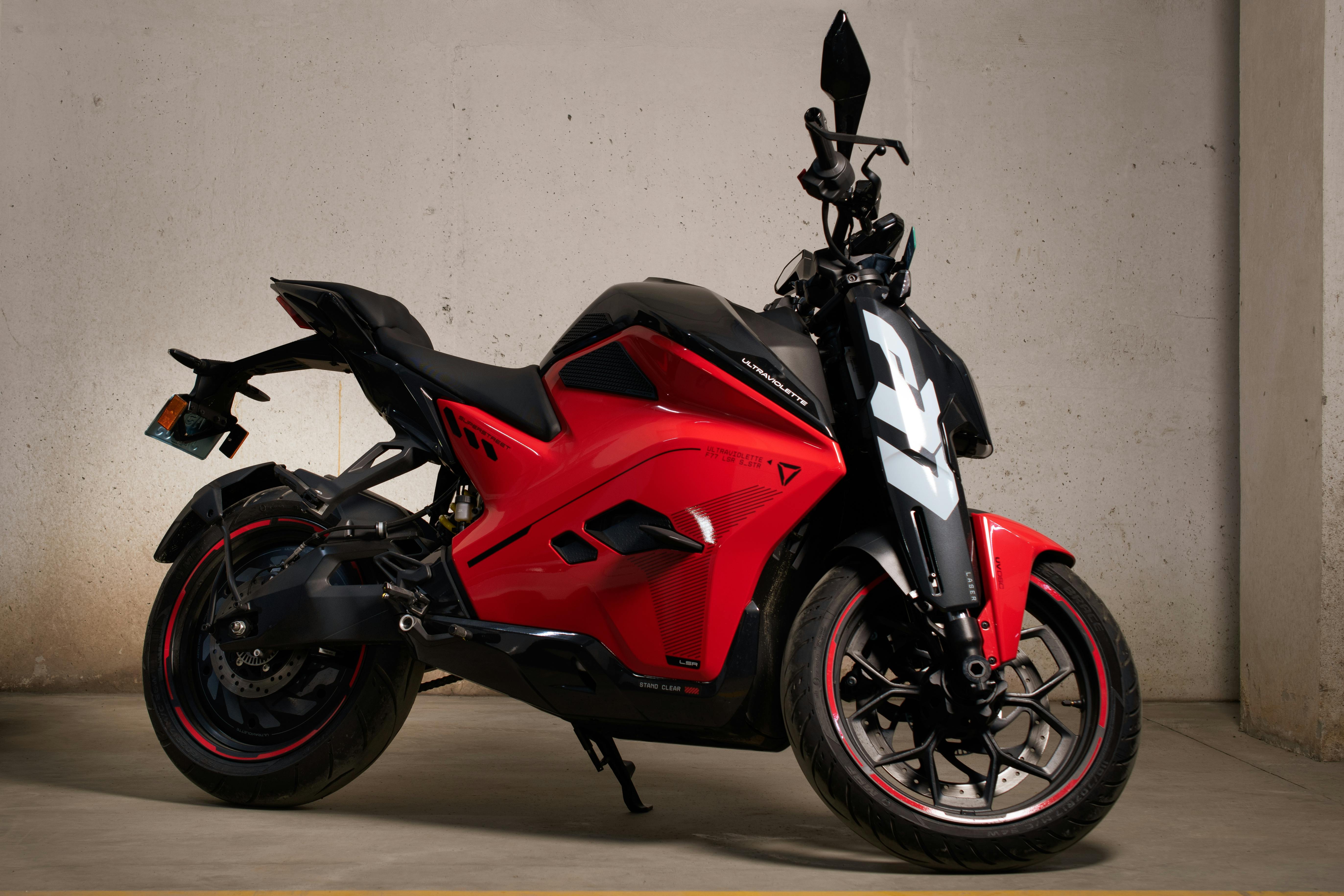Stylish red electric motorcycle with modern design parked in a garage setting.