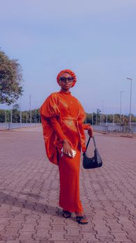 Fashionable woman in bright orange attire posing confidently outdoors. Urban fashion and expression.