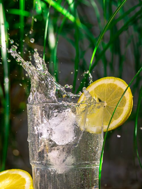 Free A refreshing lemon water splash in a glass with ice cubes, perfect for a summer day. Stock Photo
