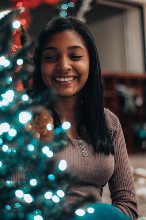 무료 크리스마스 트리 옆에 웃는 여자의 선택적 초점 사진 스톡 사진