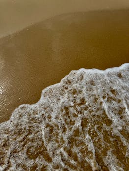 A serene capture of waves gently lapping the sandy shore in Alicante, Spain.