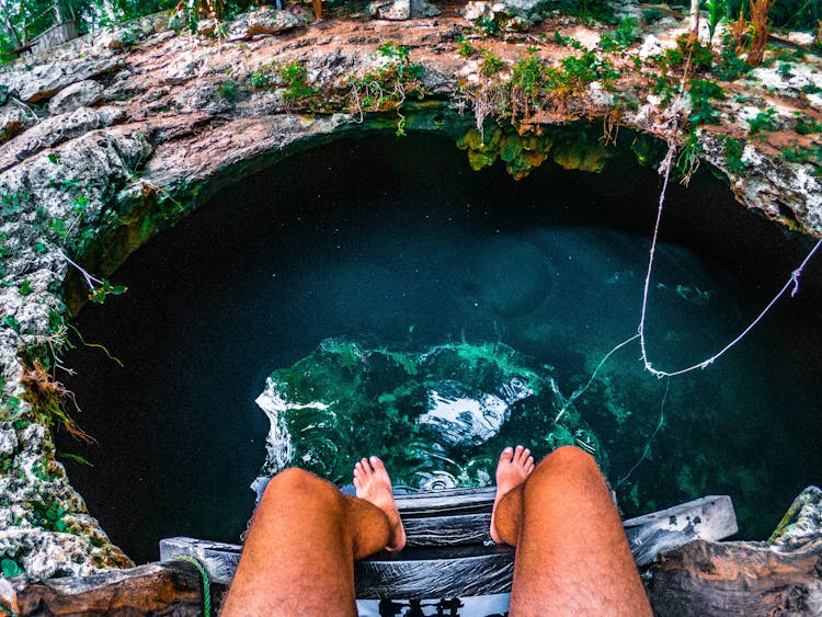 Person Sitting On A Ladder With View Of Underground Water