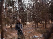 一位沉思的女人站在宁静的森林里，四周都是树木