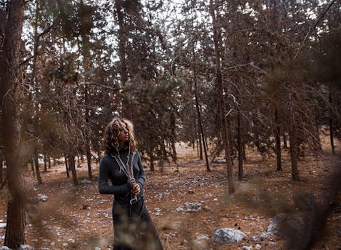 一位沉思的女人站在宁静的森林里，四周都是树木