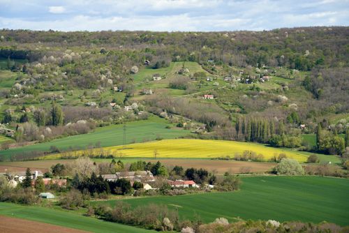 Free Idyllic springtime view of Nagygörbő with blooming fields and rolling hills. Stock Photo