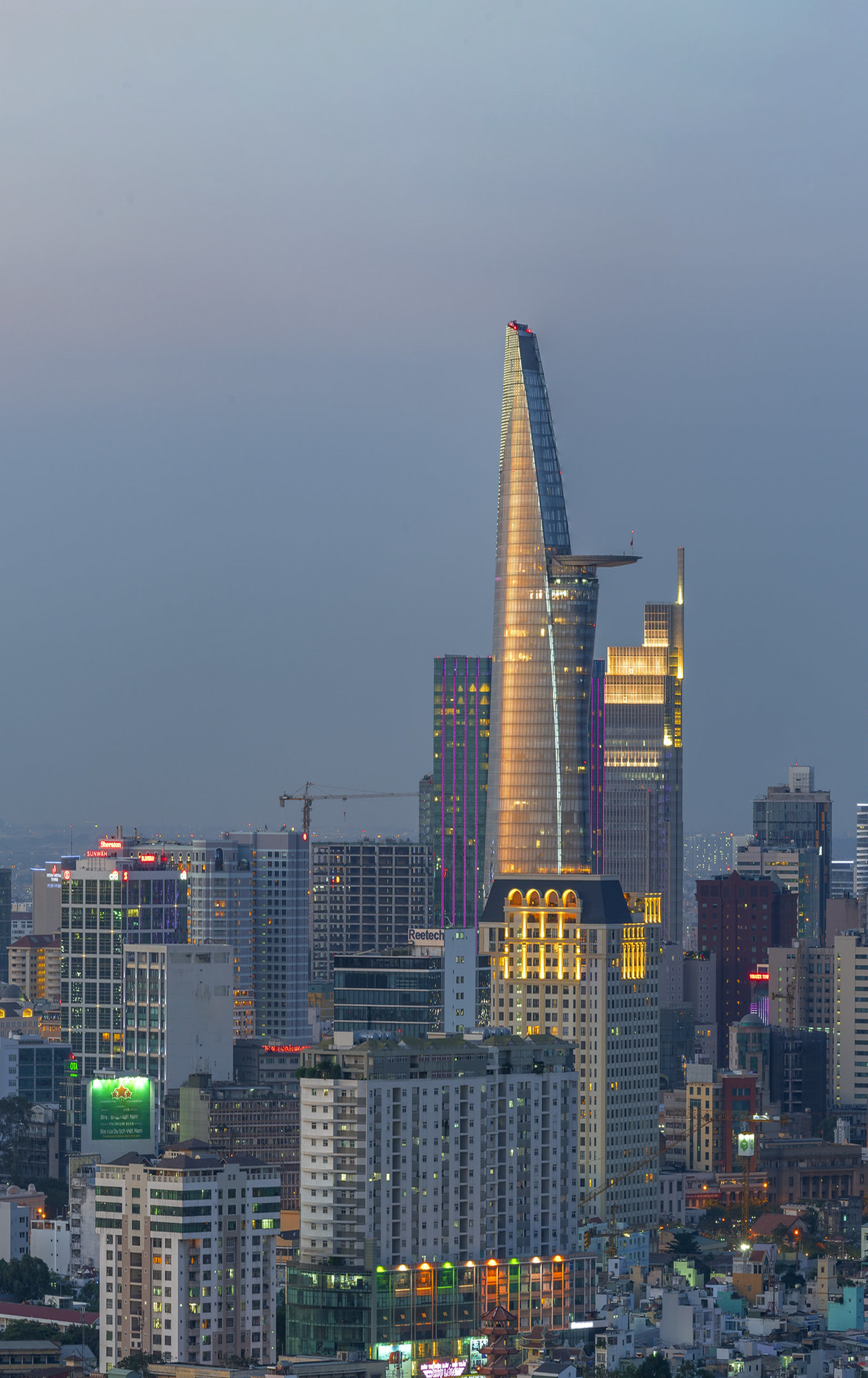 Skyline view of Ho Chi Minh City featuring the iconic Bitexco Financial Tower at twilight.