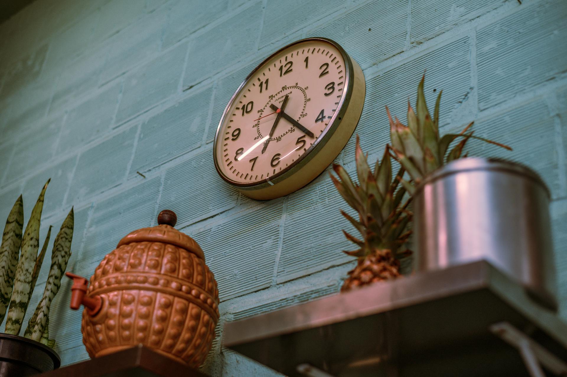 Stylish vintage wall clock on a blue brick wall with kitchen decor.