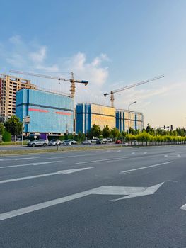 Modern construction site with cranes and blue buildings in Tianjin, China during daylight.