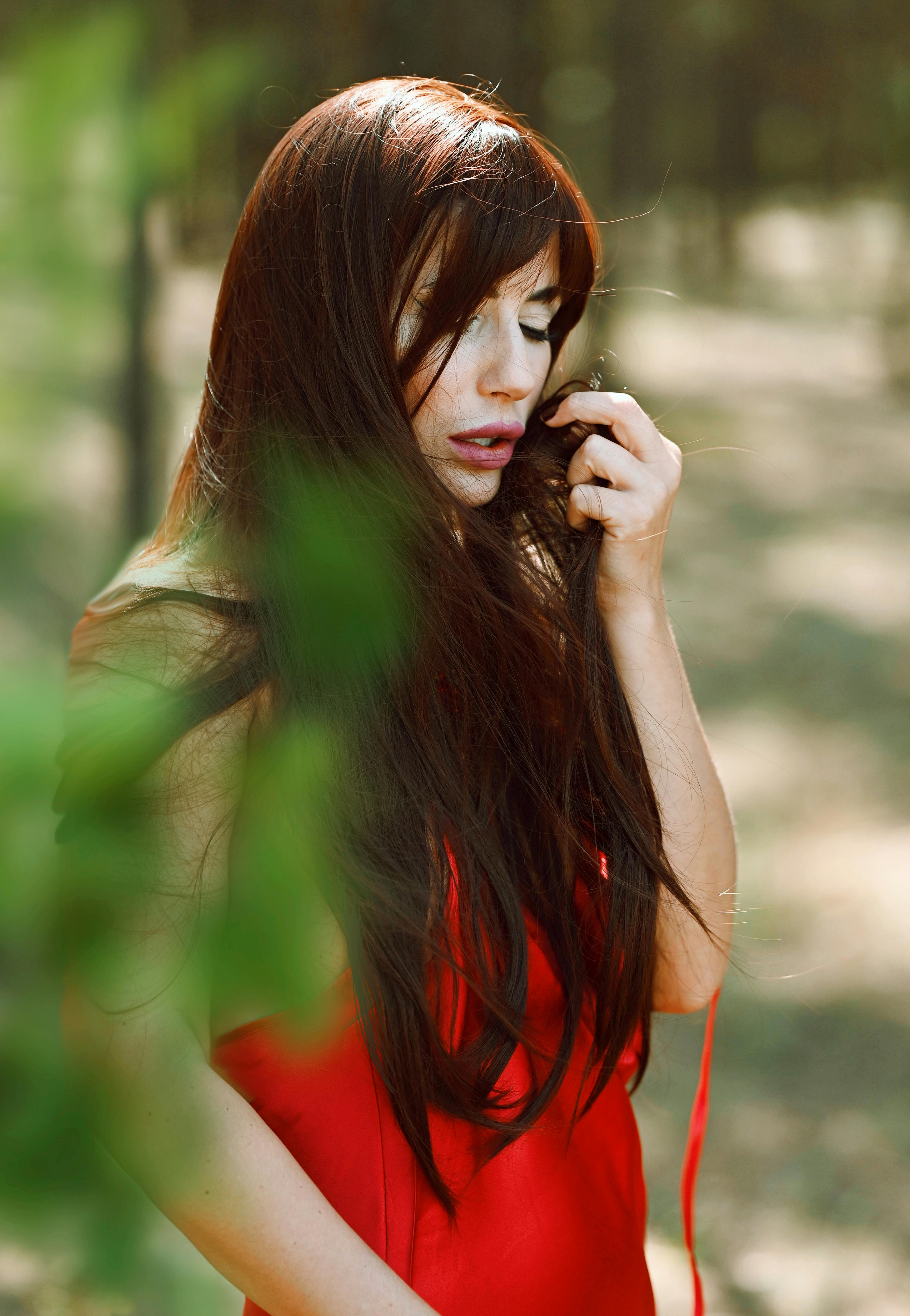 Serene portrait of a woman in a red dress surrounded by nature, evoking grace and tranquility.