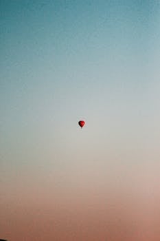 日落时分，一个孤独的热气球升起在宁静的天空中，呈现出宁静而极简的景色