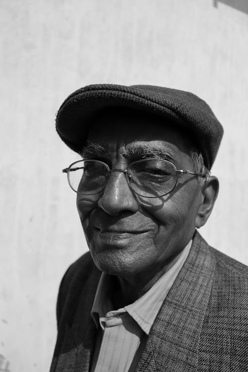 La Fotografia In Scala Di Grigi Dell'uomo Sorridente Che Indossa Il Cappello