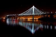 一座照明桥梁的夜间视图在城市环境中倒映在平静的水面上