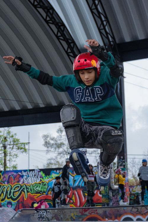 Free Teenager jumping off ramp at colorful graffiti-covered skatepark, showcasing dynamic skateboarding skills. Stock Photo
