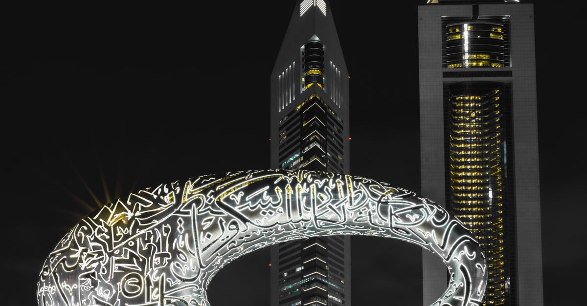Illuminated Museum of the Future against the night sky in Dubai with surrounding skyscrapers.