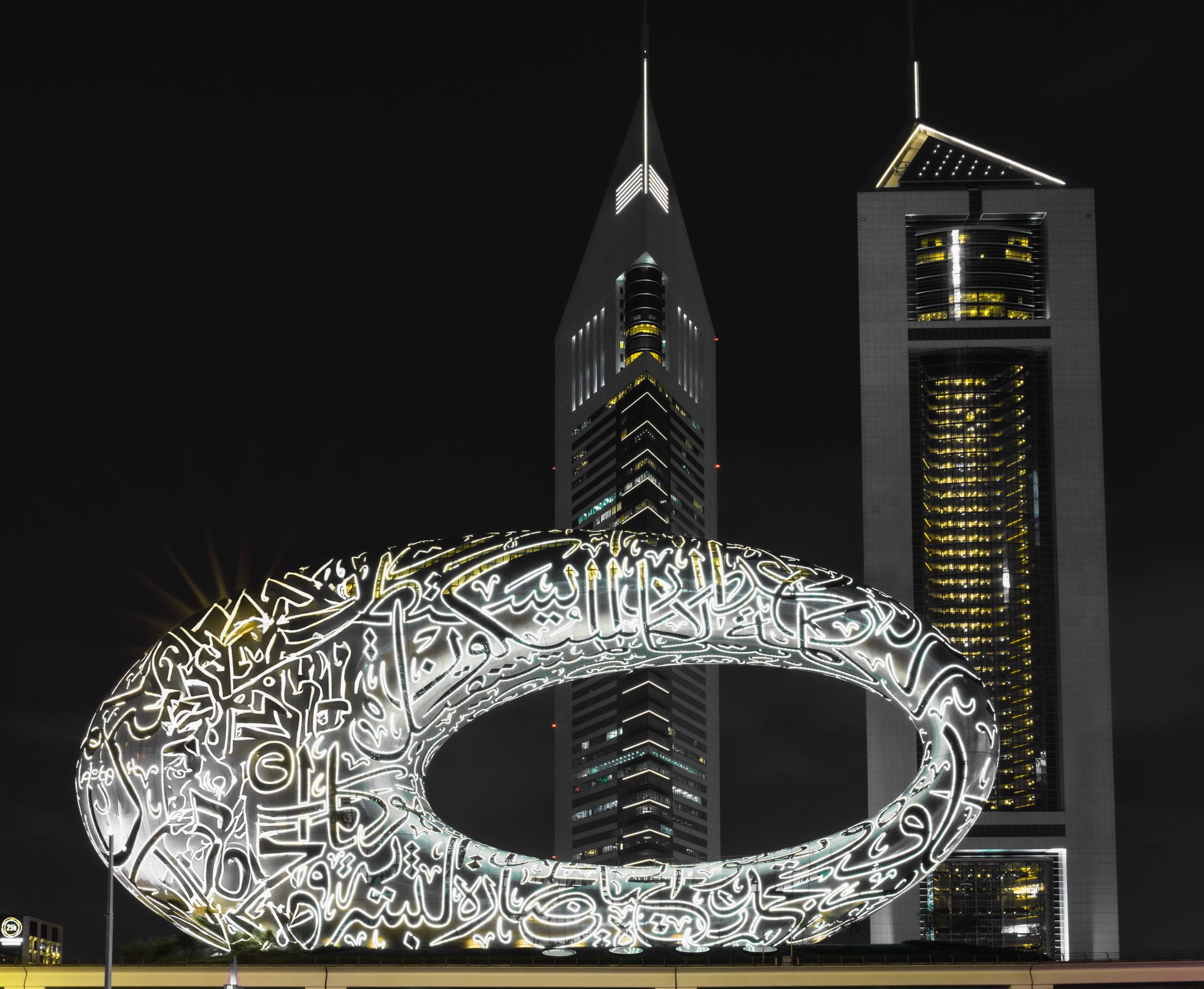 Illuminated Museum of the Future against the night sky in Dubai with surrounding skyscrapers.