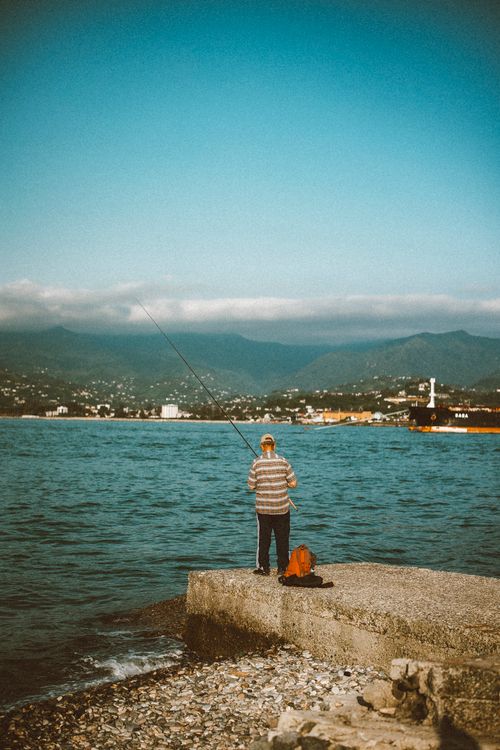 Free Serene view of an elderly man fishing by the sea in Batumi, Georgia. Stock Photo