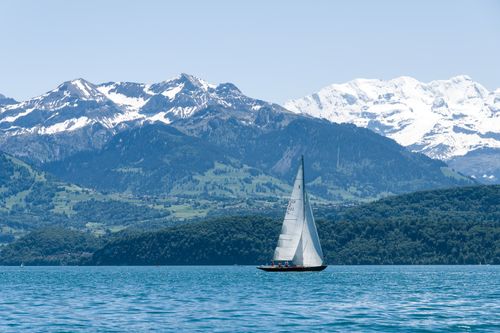 Free A serene sailboat glides across Lake Thun against a backdrop of the Swiss Alps. Stock Photo