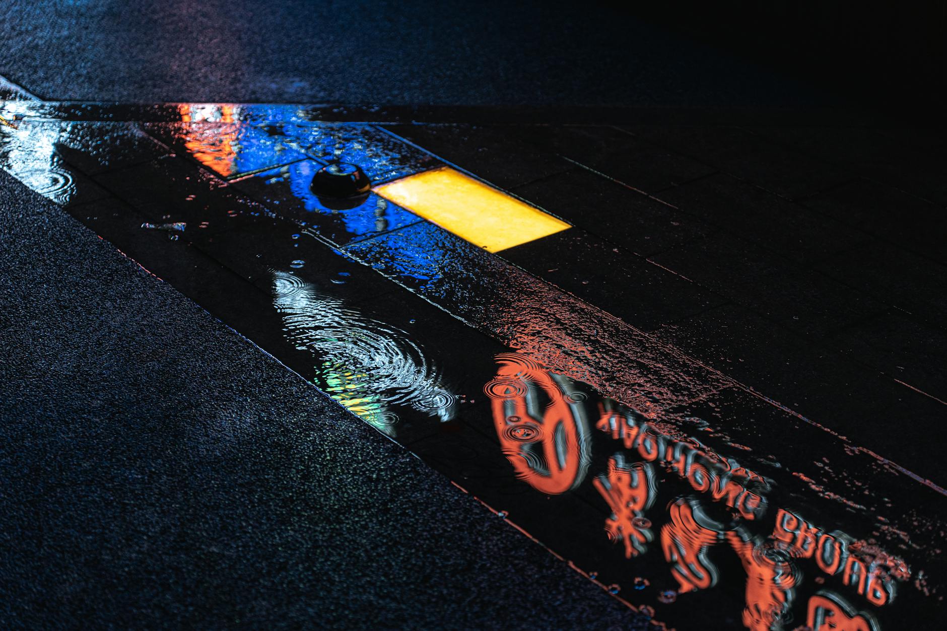 Vibrant neon signs reflect on the wet pavement at night