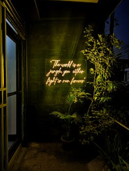 Neon text in a dark corner creates a moody atmosphere with plants.