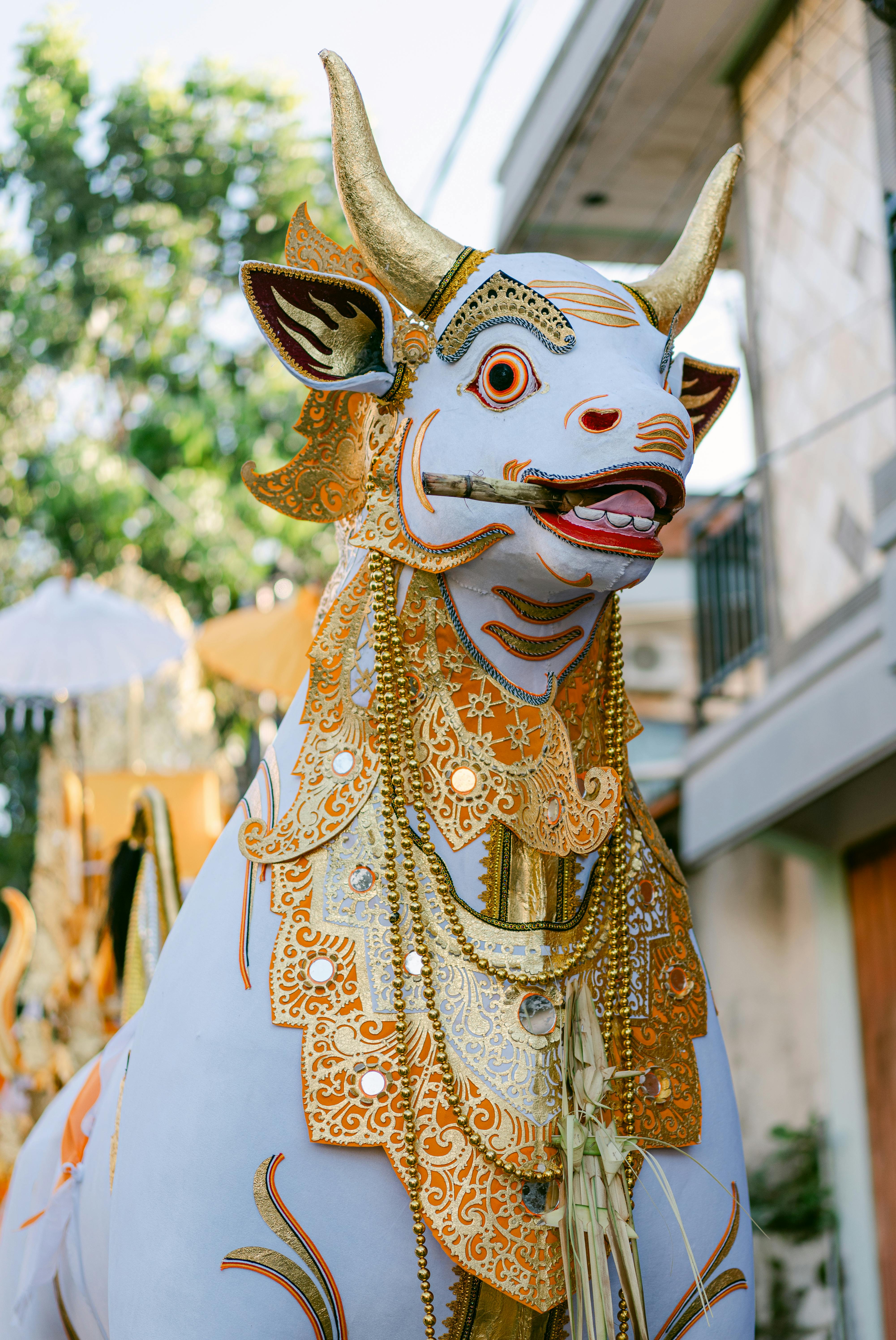grátis Estátua de um touro branco vibrante adornada com decorações douradas em uma cerimônia ao ar livre em Bali. Foto profissional