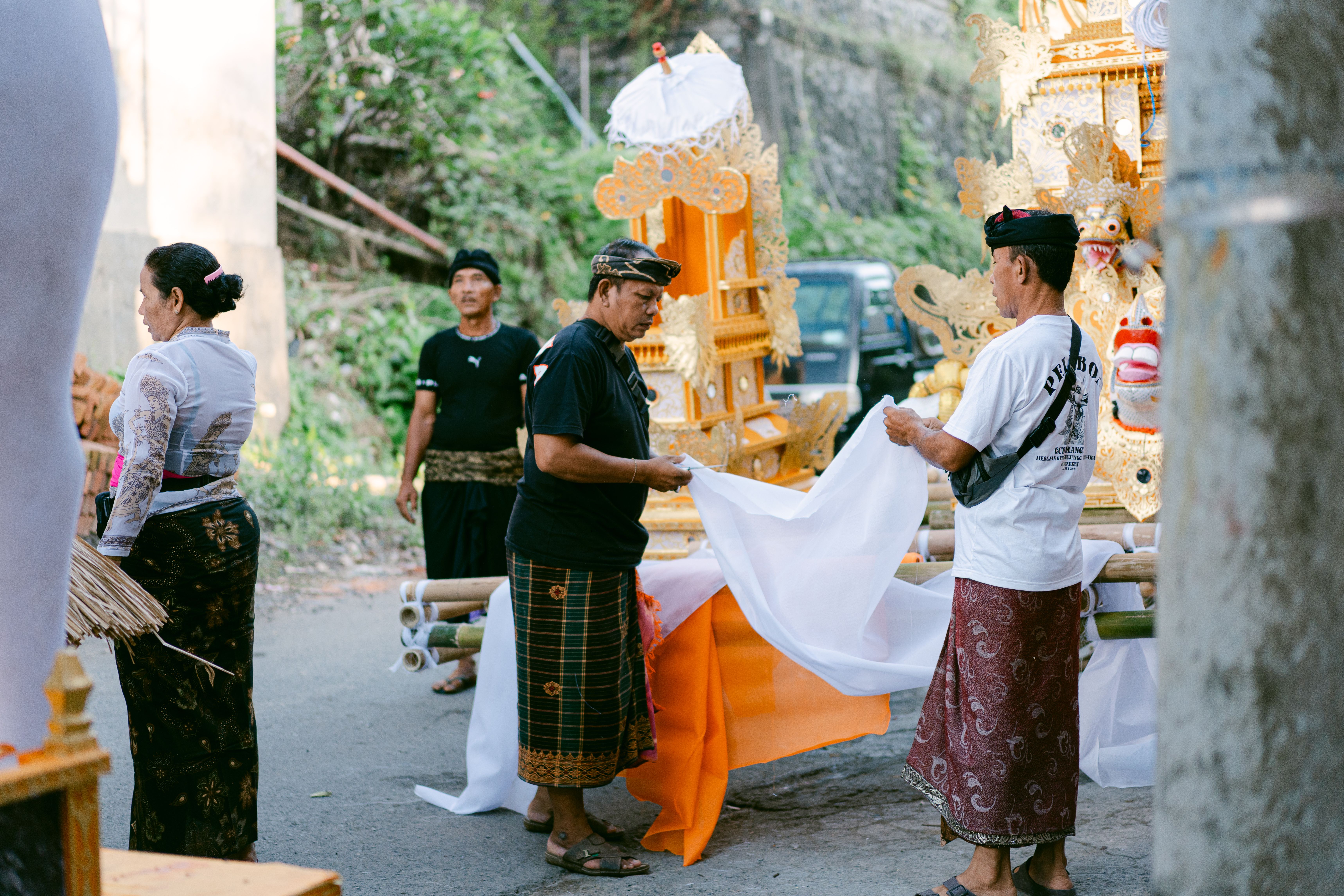 People preparing for a traditional Balinese ceremony outdoors, featuring elaborate decorations and attire.