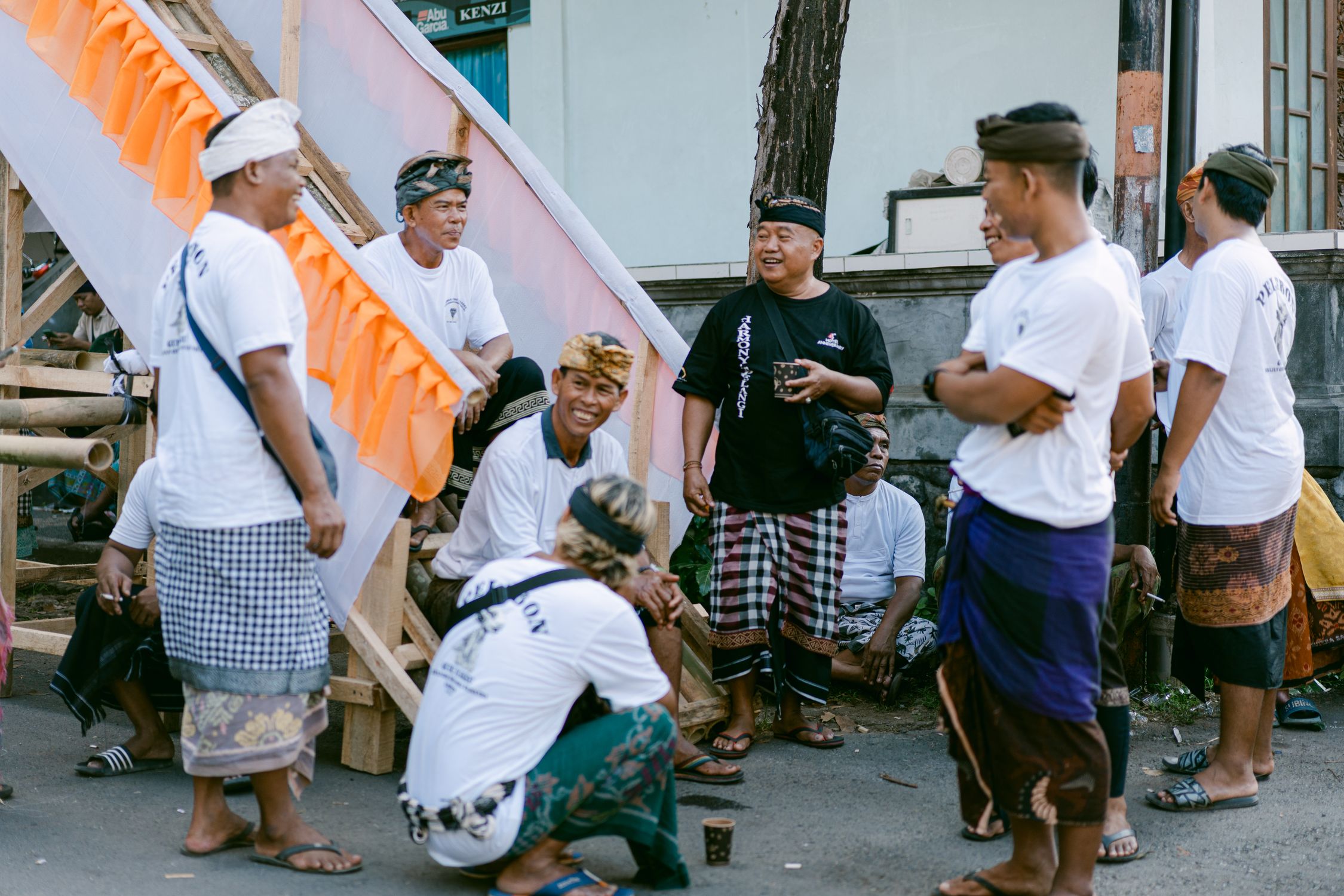 Group of Balinese men socializing outdoors in traditional clothing.