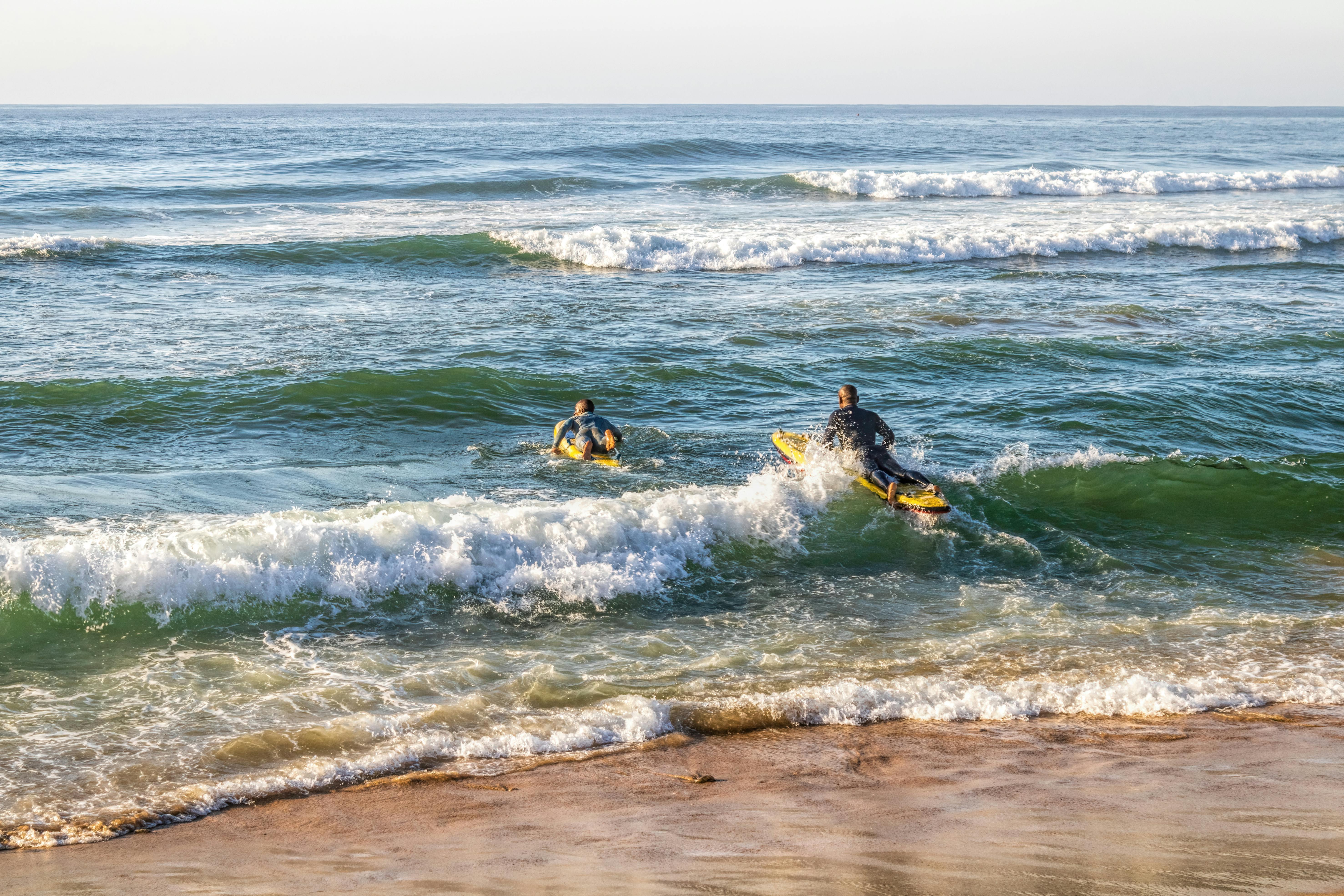Lifeguards paddle through waves during a sunny day training in Margate, South Africa.