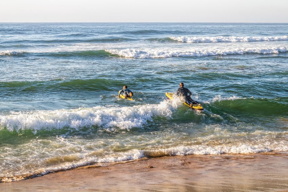 Lifeguards paddle through waves during a sunny day training in Margate, South Africa.