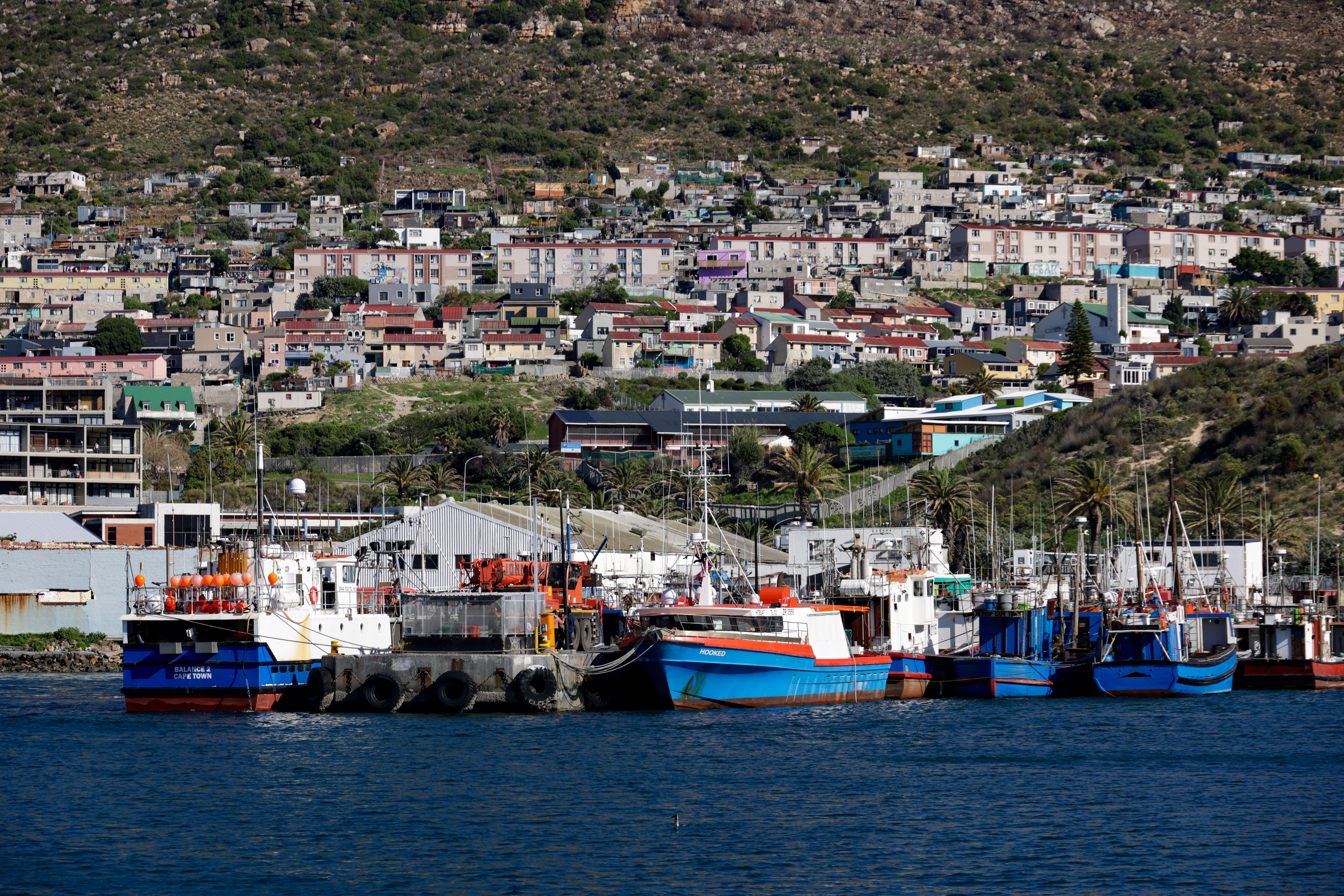 Fishing boats in Kalk Bay harbour with the village shopfronts and railway line behind