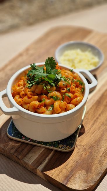 A bubbling baking dish of gruyère mac and cheese with a golden panko crust and a wooden spoon lifting out a cheesy portion.