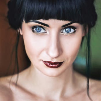 Close-up portrait highlighting striking blue eyes and red lipstick.