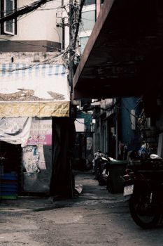 Dark, atmospheric alleyway scene in a city with motorbikes and cluttered storefronts.