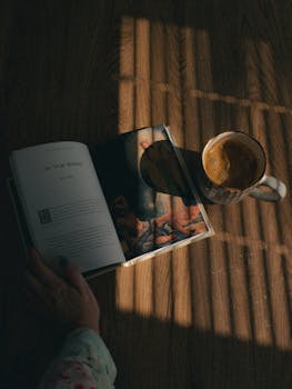 A peaceful scene of a book and coffee on a sunlit wooden table, inviting relaxation.