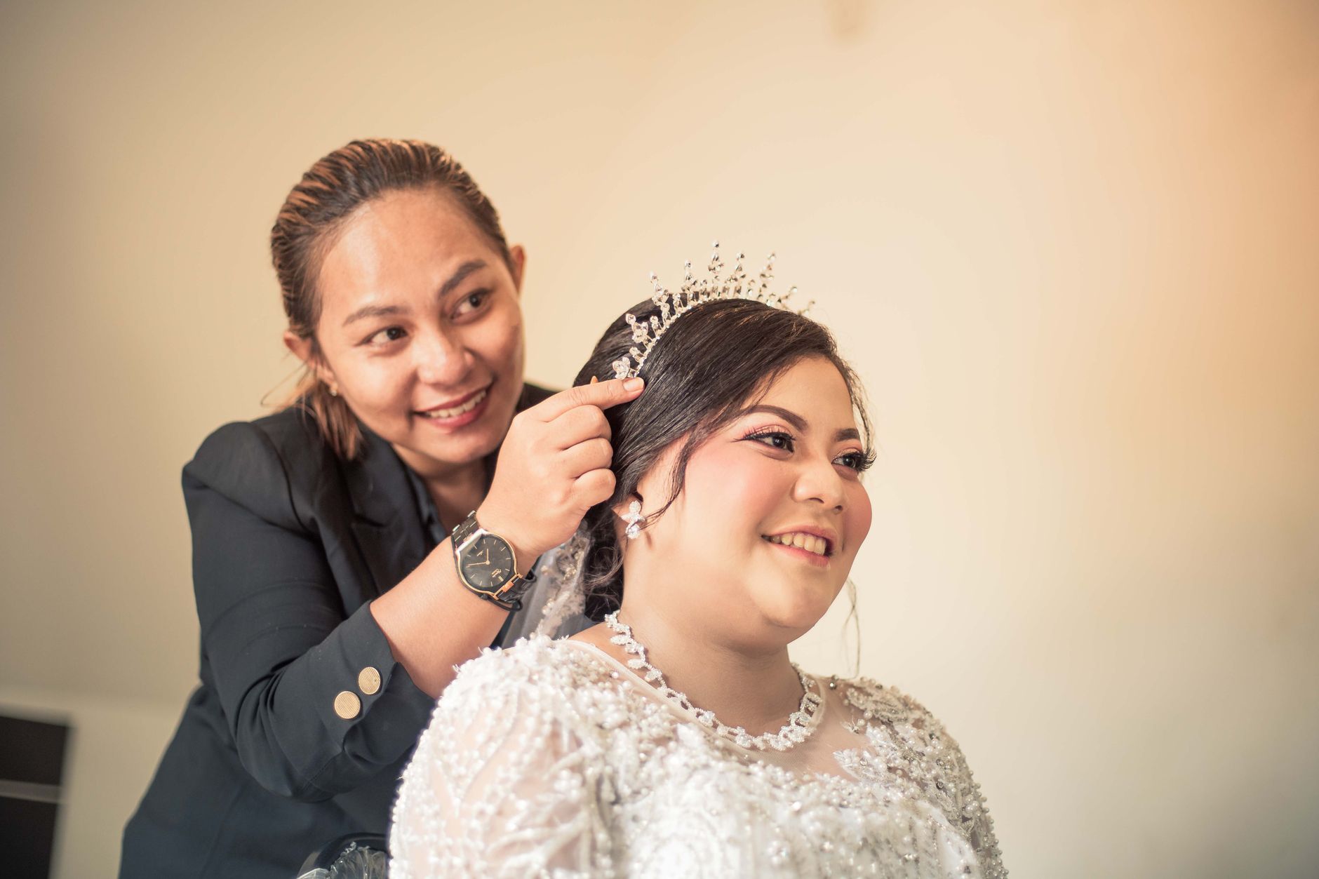 Bride and makeup artist smiling during bridal preparation, capturing a joyful moment.