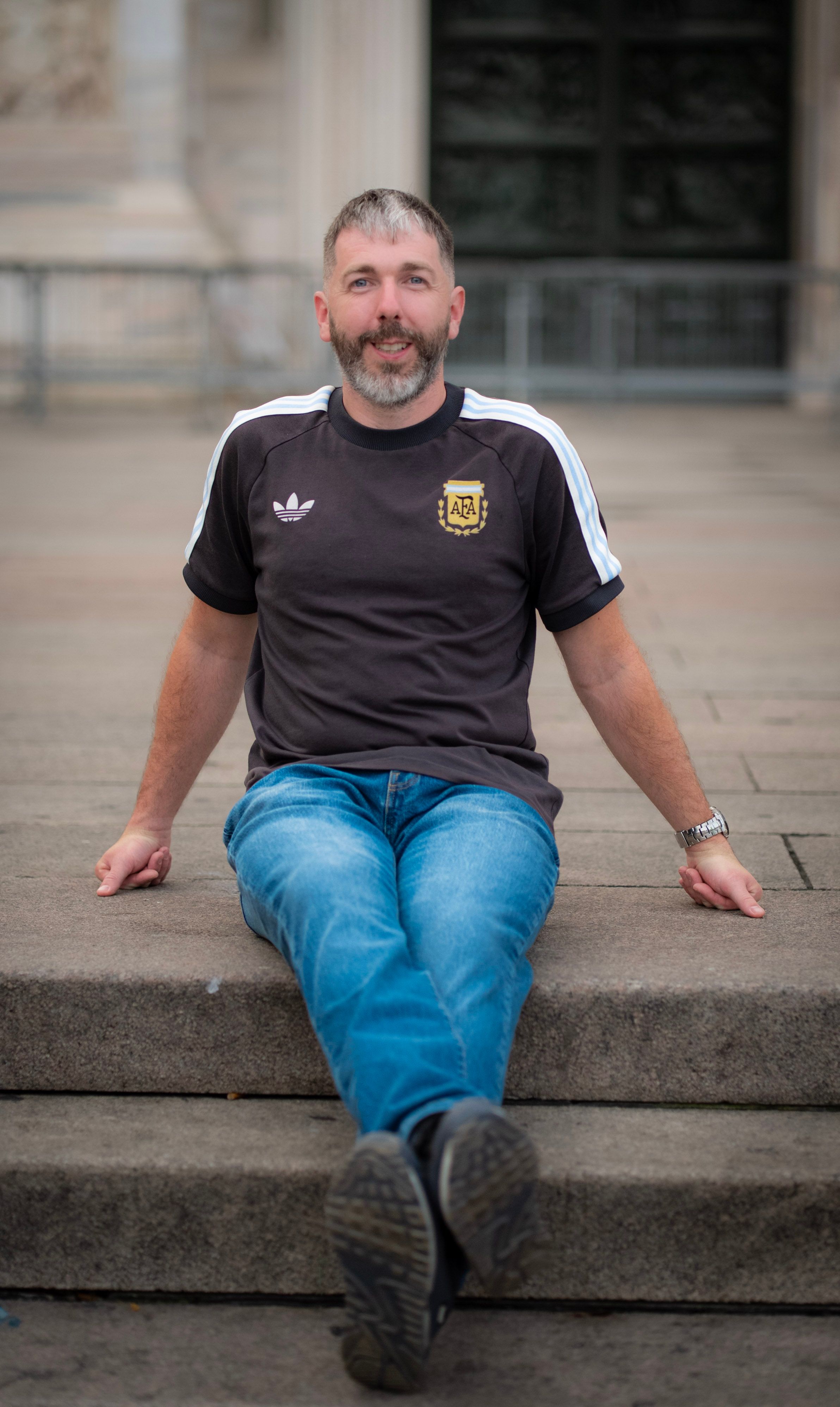 A relaxed man sits on steps in Milan, capturing a serene and casual vibe.