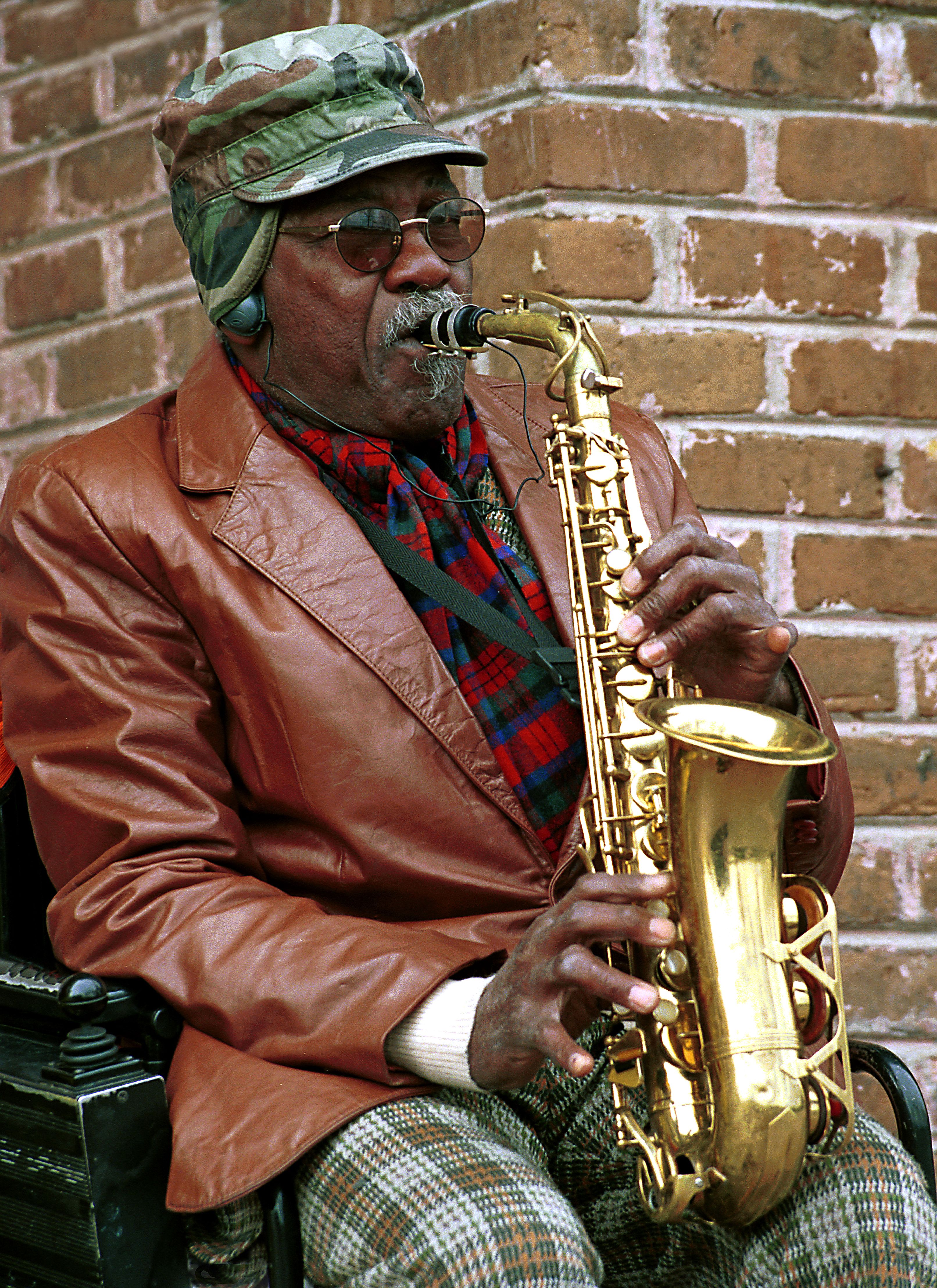 Elderly street musician playing saxophone outdoors in Savannah, Georgia.