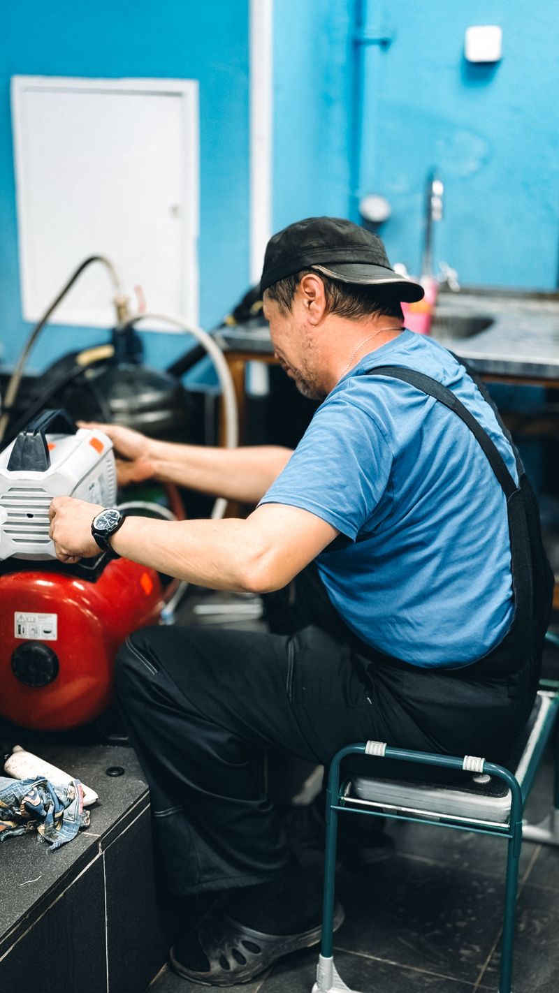 Repairman inspecting a compactor ram mechanism in a workshop