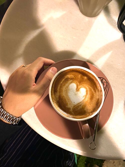 Free A hand holds a coffee cup with heart-shaped latte art, perfect for cozy cafe moments. Stock Photo