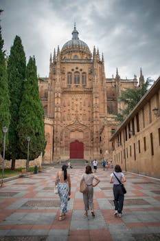 Tourists exploring the impressive Salamanca Cathedral on an overcast day in Spain.